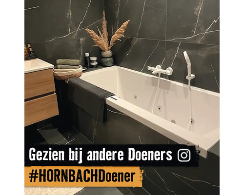 Badkamer met ligbad, wastafel en donkere marmeren tegels