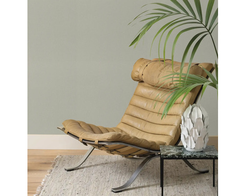 Lederen fauteuil op metalen frame naast bijzettafel met plant