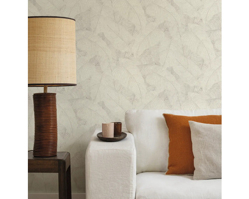 Woonkamer met bank, kussens, tafellamp en behang met bladerpatroon