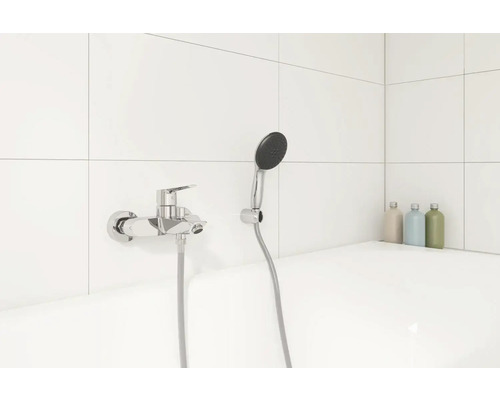 Afbeelding van een badkamer met kraan en handdouche tegen een witte tegelwand