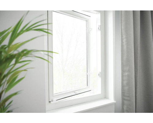 Gekanteld, wit raam met vensterbank naast gordijn en plant