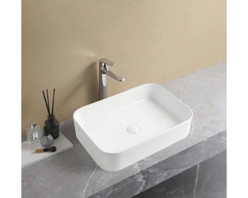 Rechthoekige keramische opzetwastafel met kraan op een werkblad