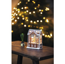 Decoratief peperkoekhuis met sneeuw en kerstboom op de achtergrond