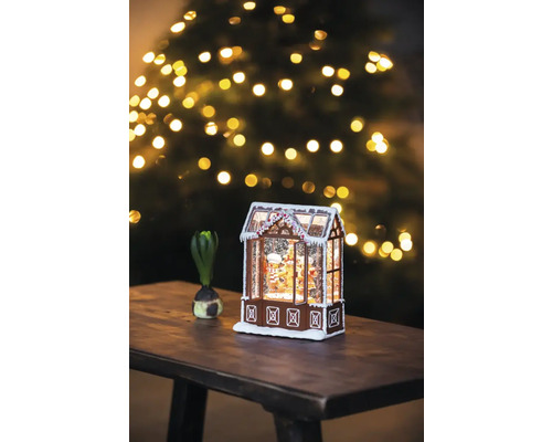 Decoratief peperkoekhuis met sneeuw en kerstboom op de achtergrond