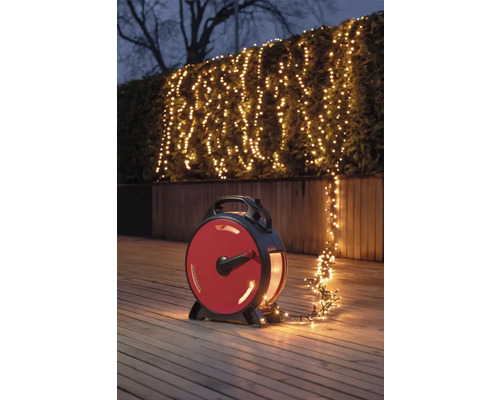 Scene met een lichtsnoer op een haspel die een struik in de tuin verlicht.