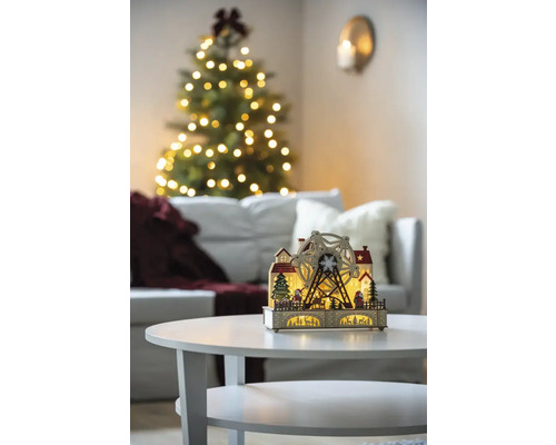 Decoratieve kerstverlichting met reuzenrad op een tafel in een woonkamer met kerstboom.