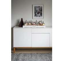Decoratieve kerstscène met huizen, bomen en trein op een wit dressoir.