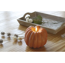 Decoratieve pompoenkaars met dienblad en bloemaccenten op een houten tafel