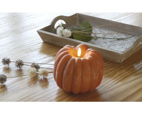 Decoratieve pompoenkaars met dienblad en bloemaccenten op een houten tafel