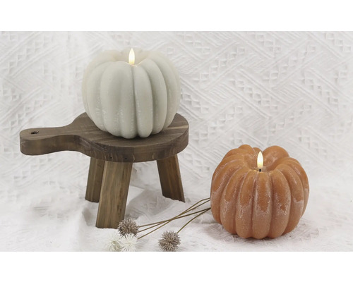Decoratieve pompoenkaarsen op een kleine houten kruk