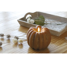Decoratieve pompoenkaars met ledlicht op een tafel met houten dienblad