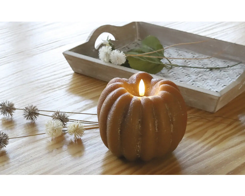 Decoratieve pompoenkaars met ledlicht op een tafel met houten dienblad