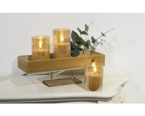 Decoratieve ledkaarsen in glazen houders op een houten dienblad met planten op een tafel