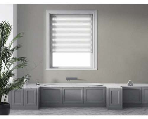 Lichte badkamer met bad, jaloezie en decoratieve plant