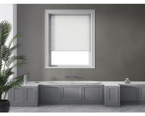 Lichte badkamer met bad, jaloezie en kamerplant.