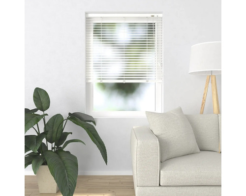 Scène met raamblindering, bank, kamerplant en vloerlamp in een heldere ruimte.