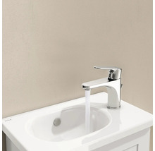 Wastafelkraan van chroom met water uit de kraan op een witte wastafel