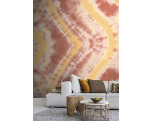 Woonkamer met behangmotief, bank en bijzettafels.