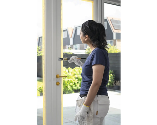 Vrouw schildert deurkozijn met een kwast. Schilderwerkzaamheden in huis.