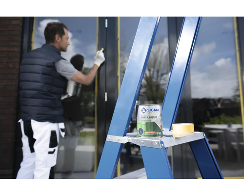 Man schildert raamkozijn met verf van Sigma Coatings, verfblik staat op ladder