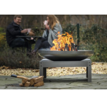 Vuurplaats in de tuin met brandend hout en twee personen op de achtergrond