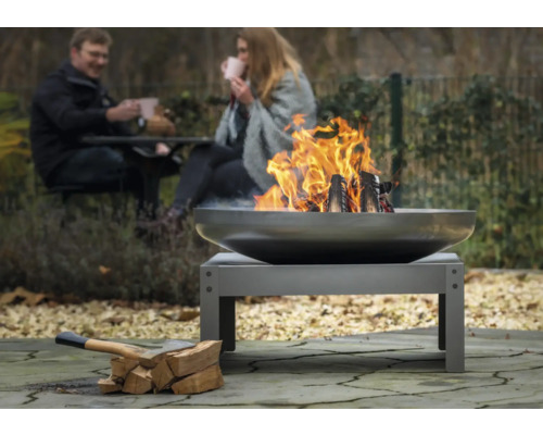 Vuurplaats in de tuin met brandend hout en twee personen op de achtergrond