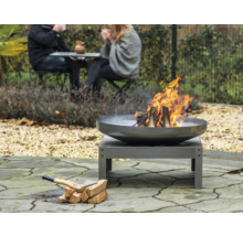 Vuurplaats in de tuin met brandend hout en een bijl naast een stapel hout