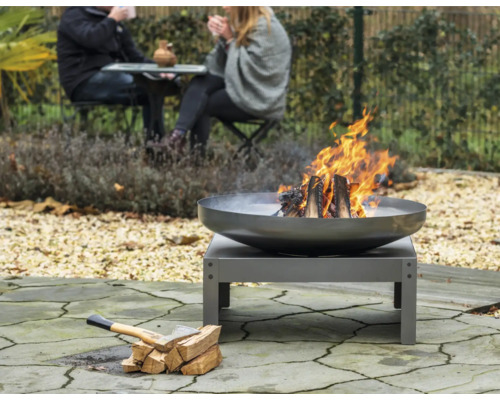 Vuurplaats in de tuin met brandend hout en een bijl naast een stapel hout