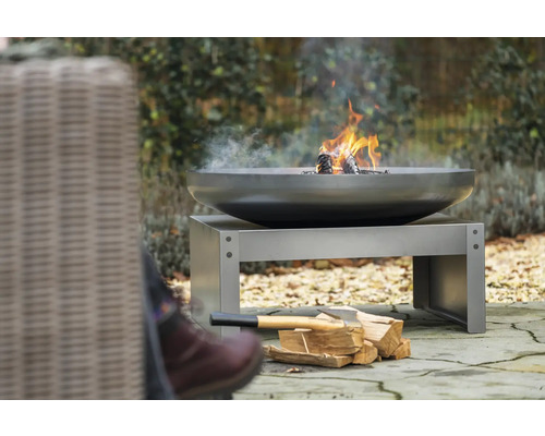 Vuurschaal met hout op een metalen sokkel in de tuin.