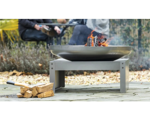 Metalen vuurplaats met brandend hout en houtblokken buitenshuis