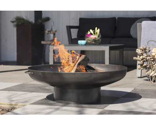 Metalen vuurschaal met hout en vlammen in de tuin