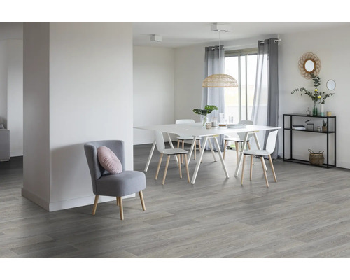 Lichte eetkamer met eettafel, stoelen en vloer in houtlook, evenals een fauteuil