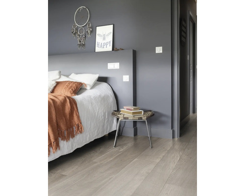 Slaapkamer met bed, nachtkastje en een lichte houten vloer.