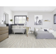 Lichte kamer met houten vloer, bad, bed en een vrouw