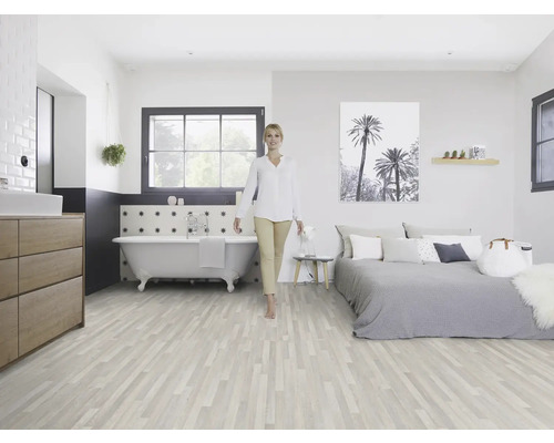 Lichte kamer met houten vloer, bad, bed en een vrouw