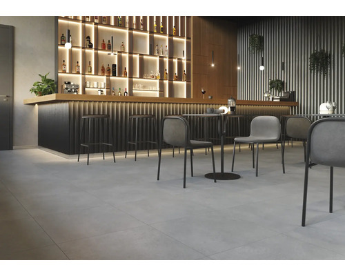 Interieur met bar, barkrukken, tafels en stoelen op een tegelvloer.