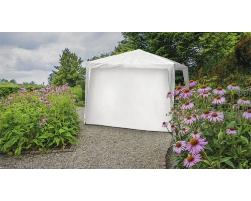 Witte partytent in de tuin tussen bloemperken