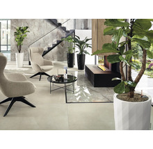 Modern interieur met fauteuils, tafel, planten en open haard.