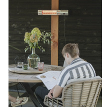 Terras met terrasverwarmer aan houten wand en persoon aan tafel