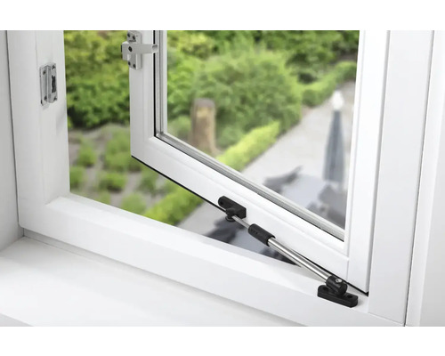 Geopend wit raam met raambeslag en uitzicht op groen