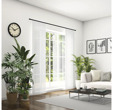 Lichte woonkamer met bank, salontafel, kamerplanten, klok en schuifgordijn voor het raam.