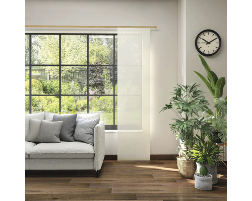 Woonkamer met bank, kamerplanten, klok en schuifpaneel voor het raam