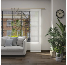 Woonkamer met bank, kamerplanten, klok en schuifpaneel voor het raam