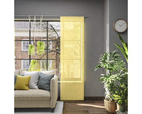 Woonkamer met schuifgordijn voor het raam, bank, kamerplanten en wandklok