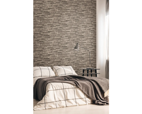 Slaapkamer met steenlook behang, bed, nachtkastje en lamp.