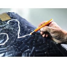 Hand die met een Pica stift op een folie met zwarte objecten schrijft