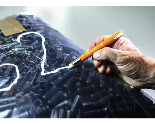Hand die met een Pica stift op een folie met zwarte objecten schrijft