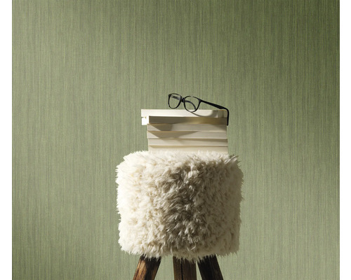 Decoratieve scène met een kruk waarop boeken en een bril liggen, voor een gestructureerde wand