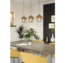 Eettafelscène met drielamps hanglamp, planten en gele stoelen.