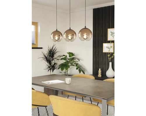 Eettafelscène met drielamps hanglamp, planten en gele stoelen.